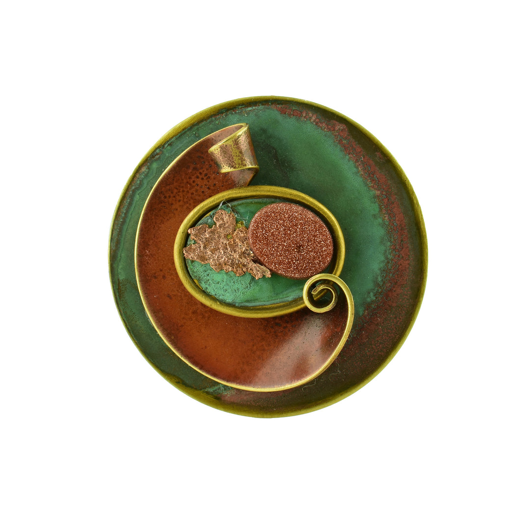Original Wind Brooch - a circle of copper tarnished with green and brown using various techniques to create color and a copper leaf in the middle.