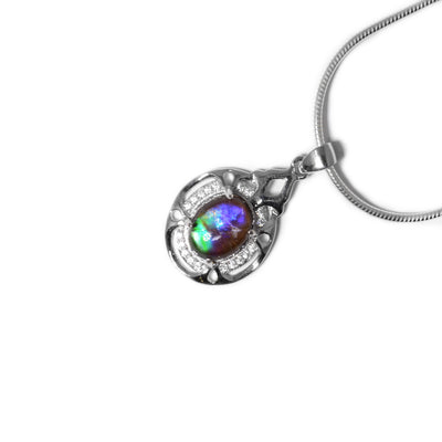 Oval piece of ammolite set in oval sterling silver frame. Frame has cubic zirconia and ornate design. Ammolite shines different colours depending on how you look at it.