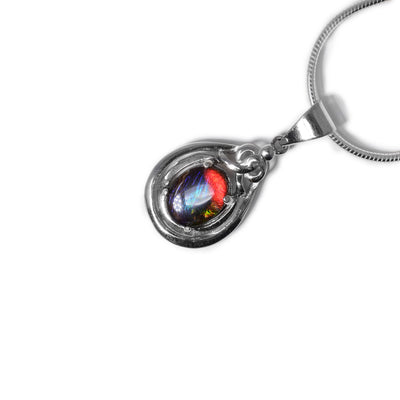 Oval piece of ammolite set in oval sterling silver frame. Frame has ornate design on top. Ammolite shines different colours depending on how you look at it.