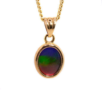 An oval ammolite pendant handcrafted out of ammolite and 14K gold. Measures 5/8"x1/4" including the bail.