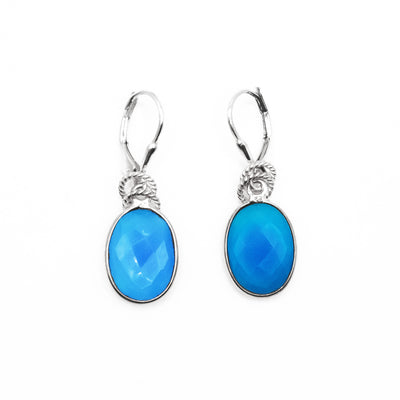 A faceted, oval blue chalcedony set in silver dangles from both lever-back hooks. Two rope-pattern rings rest above both gems. All metal is sterling silver.