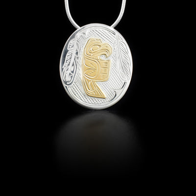 Sterling silver pendant featuring flying 14K yellow gold eagle. Two feathers carved on either side of eagle and cross-hatching background.