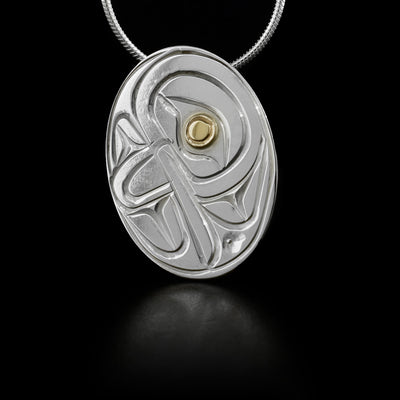 Flat, oval sterling silver pendant featuring hummingbird with 14K yellow gold in eye. Hidden bail on back.