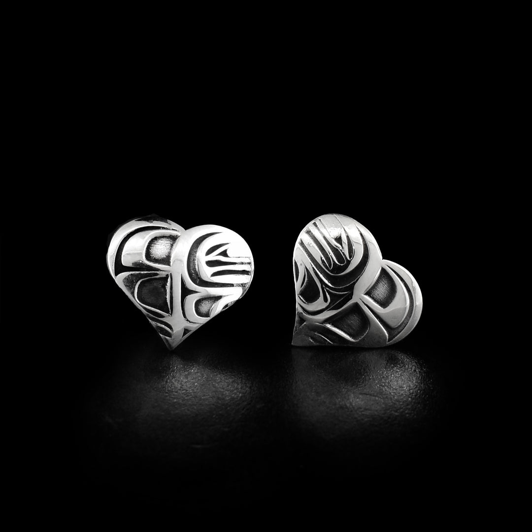 These sterling silver heart earrings are studs with large heart shaped surfaces. There are depictions of the Orca cast into the surface of the earrings. There is oxidized silver in the wells of the carvings.