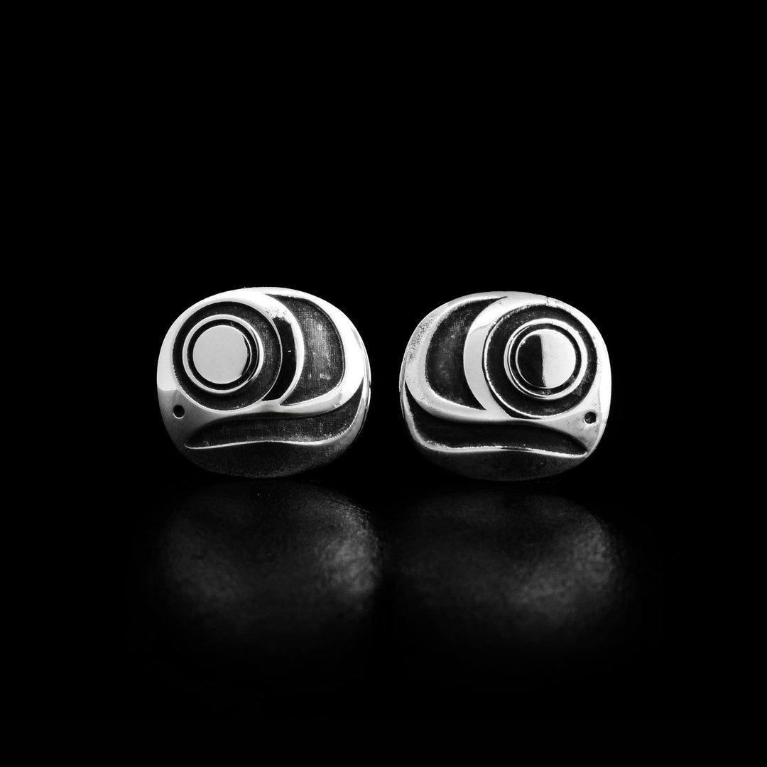 These circle stud earrings are made from oxidized silver and sterling silver. There are depictions of the Salmo egg that have been cast into the surface of the earrings.