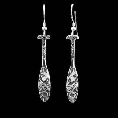 These wolf earrings are in the shape of a canoe paddle and depict the Wolf carved onto them. The background has been oxidized to give depth.