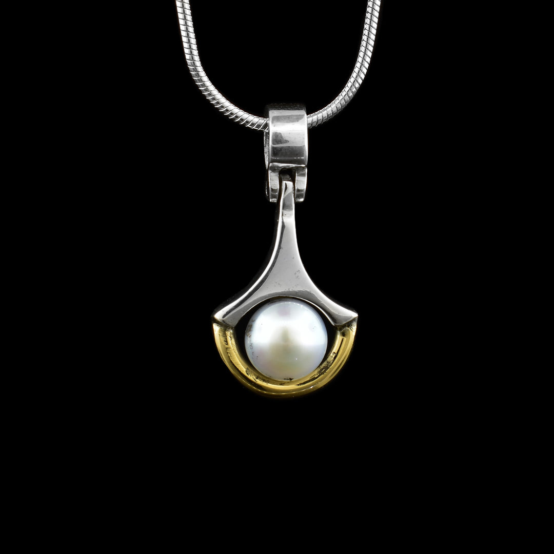 Handcrafted sterling silver and 14k gold pearl pendant designed by artist Ivan Dobren. Features a sleek two-tone frame and luminous pearl. Shop online today.