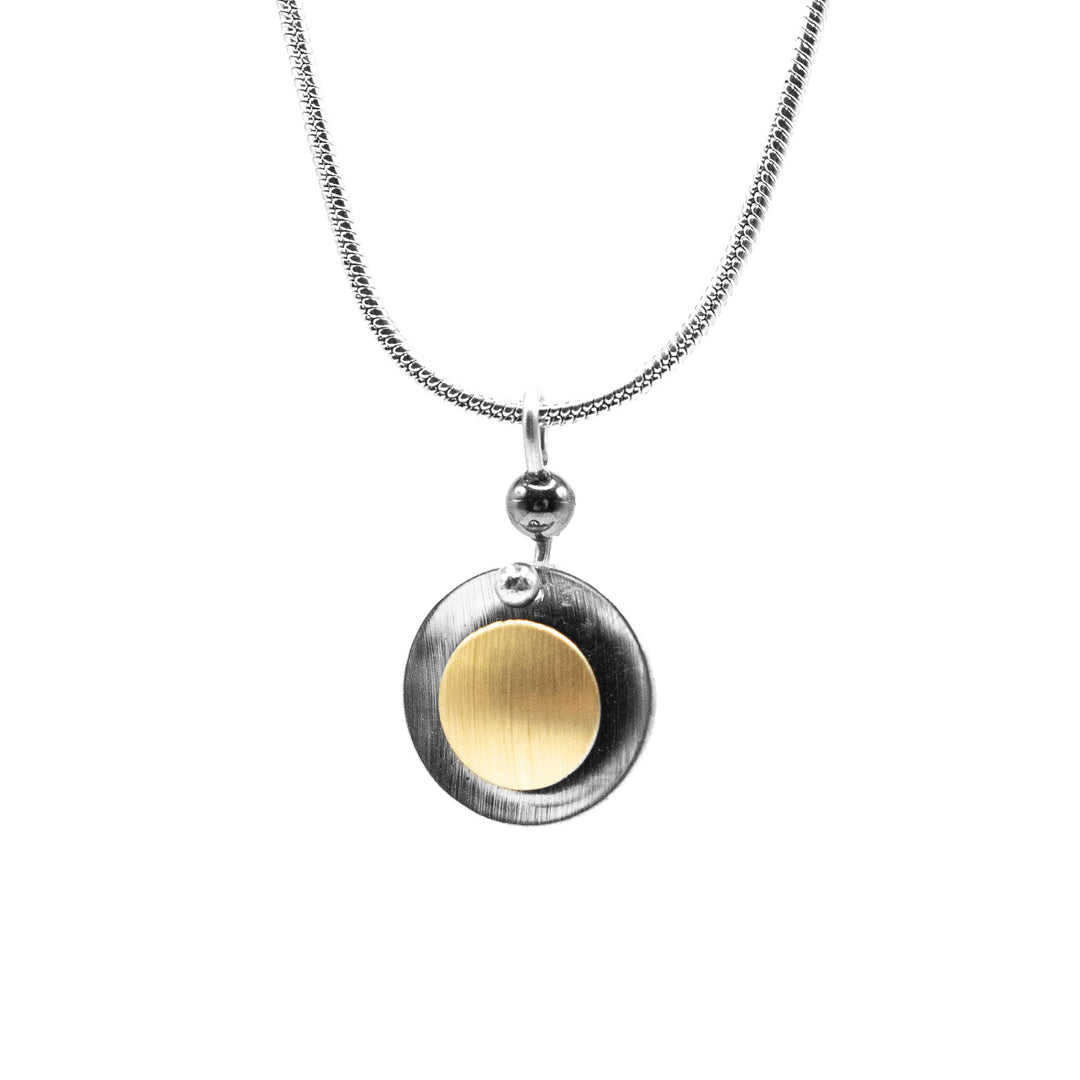 Brushed and anodized aluminum. Grey circle with smaller, gold-coloured circle on front. Stainless steel snake chain included. By JR Franco.