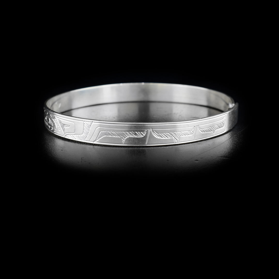 Left side of bracelet with carved designs that resemble a wing.