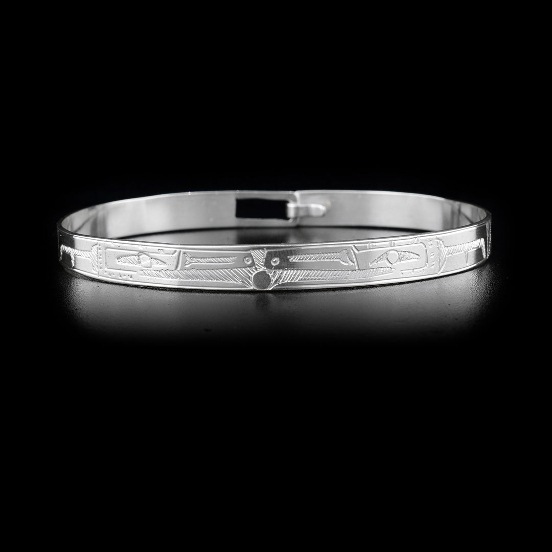 This double Raven bracelet is made from sterling silver and has a single, thin band with a clasp in the back. There are two depictions of the Raven facing each other carved into the surface of the band.