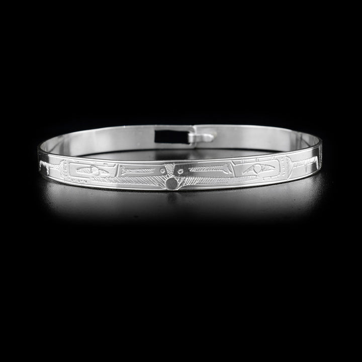 This double Raven bracelet is made from sterling silver and has a single, thin band with a clasp in the back. There are two depictions of the Raven facing each other carved into the surface of the band.