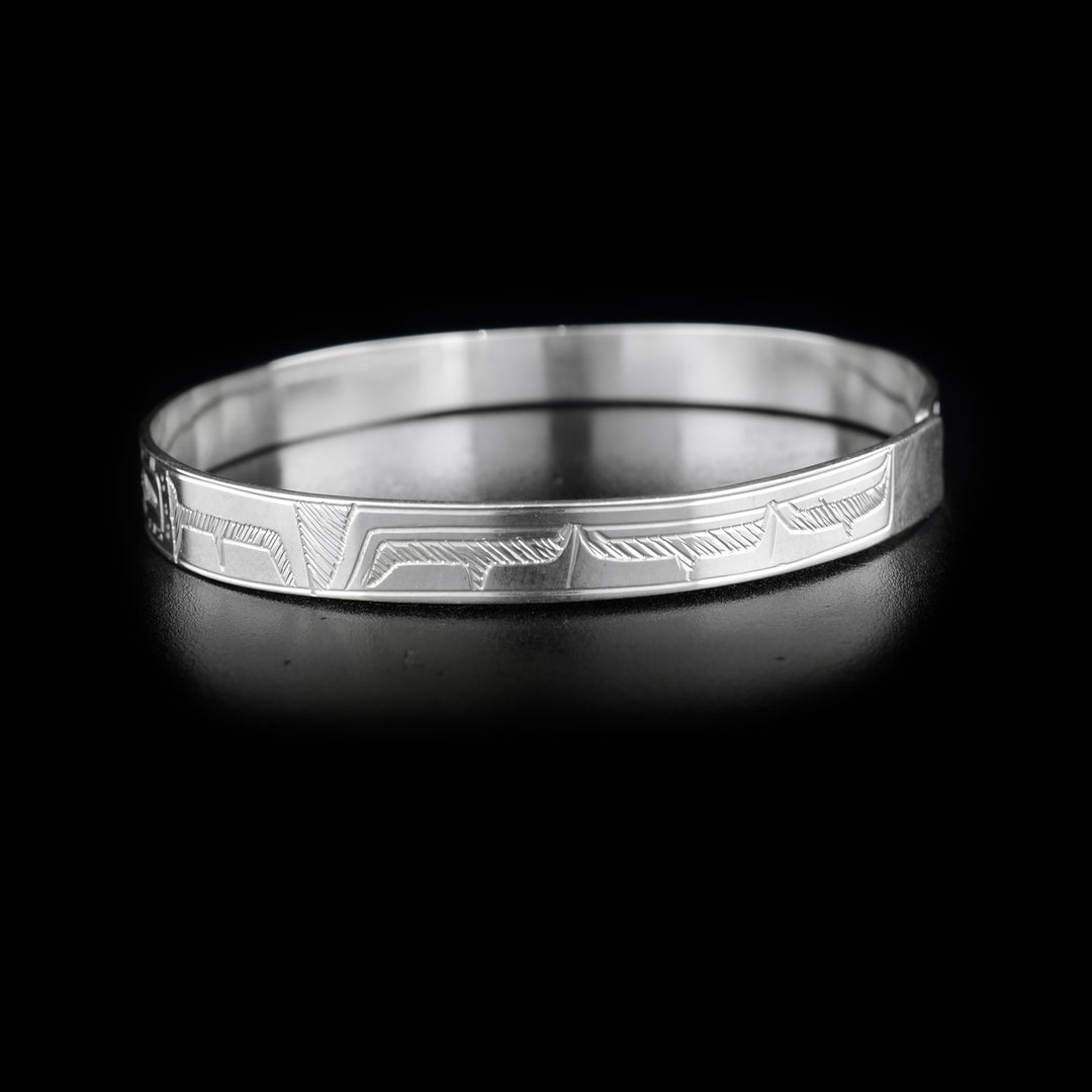 This double Raven bracelet is made from sterling silver and has a single, thin band with a clasp in the back. There are two depictions of the Raven facing each other carved into the surface of the band.