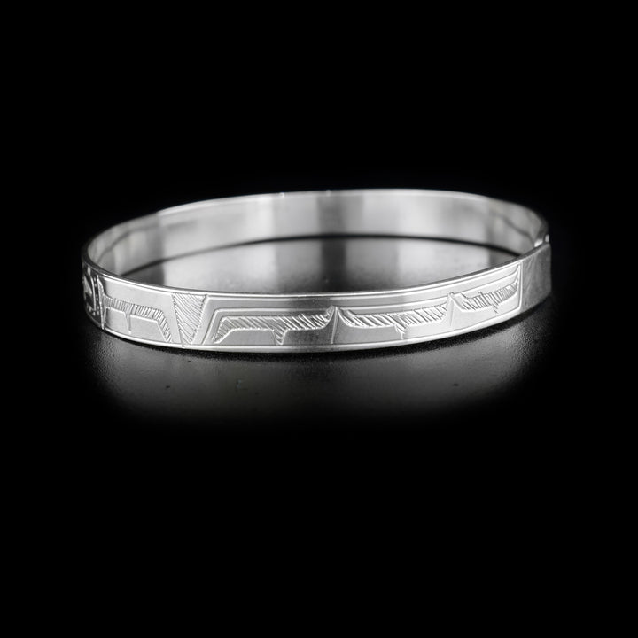 This double Raven bracelet is made from sterling silver and has a single, thin band with a clasp in the back. There are two depictions of the Raven facing each other carved into the surface of the band.