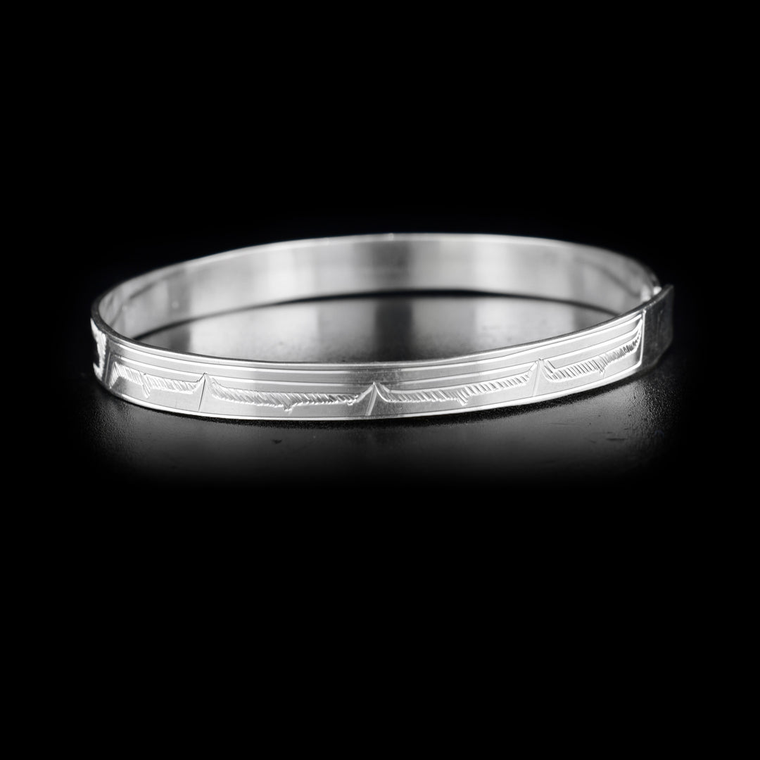Left side of bracelet with carved designs that resemble a wing.