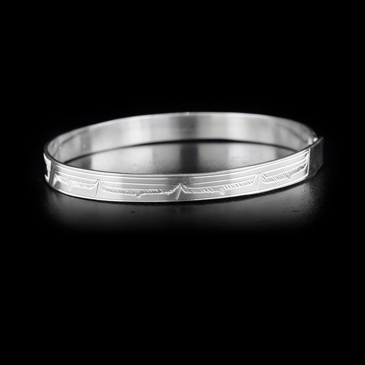 Left side of bracelet with carved designs that resemble a wing.