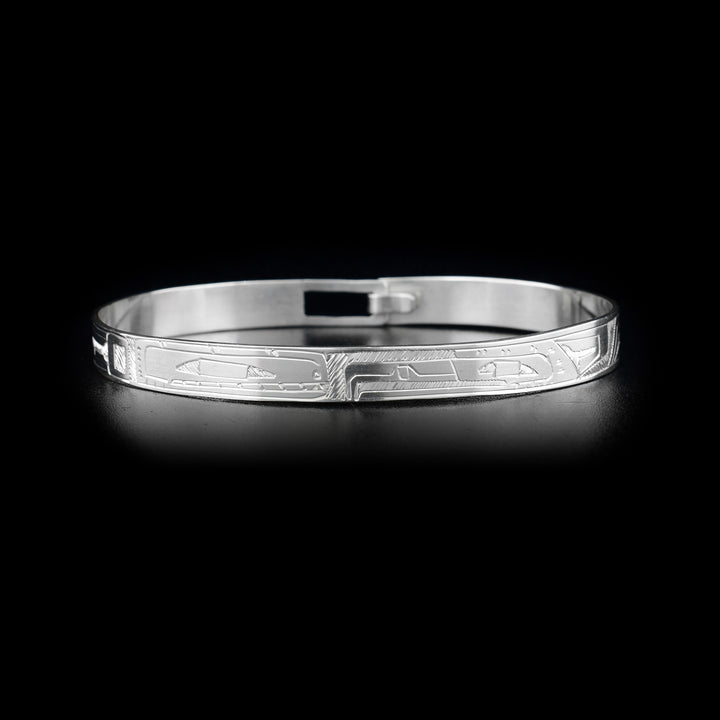 This Orca and Eagle bracelet bangle is made from sterling silver and has a thin band with a clasp in the back. There are carvings on the surface of the band that depict the Eagle and the Orca facing each other. 