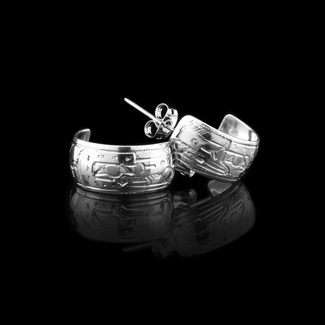 sterling silver raven hoop earrings featuring intricate Raven engravings, with the Raven’s head facing the stud and a pearl delicately held in its beak. 
