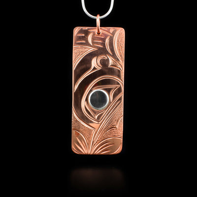 This hummingbird pendant is rectangular in shape and depicts the head of a hummingbird with a small beak drinking from a flower. Above is the bird's wing. The eye of the hummingbird is silver.