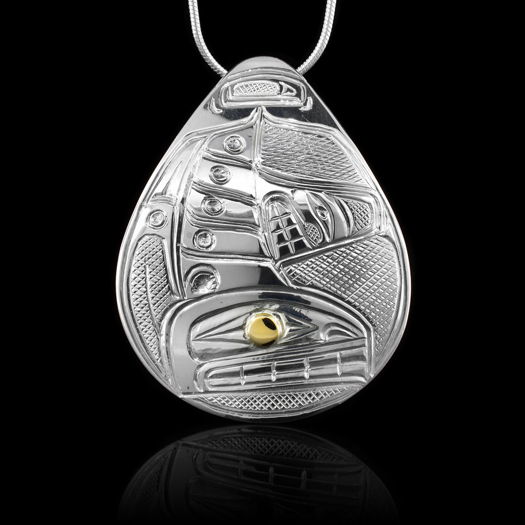 This Orca whale pendant is made from sterling silver and 14K gold and has a large teardrop shape. There is a depiction of the Orca carved into the surface of the pendant and the eye of it is made from a gold stud.