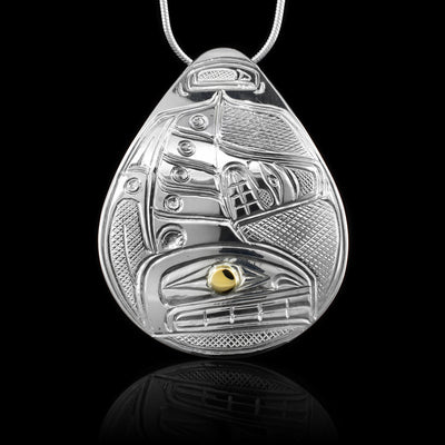 This Orca pendant is made from sterling silver and 14K gold and has a large teardrop shape. There is a depiction of the Orca carved into the surface of the pendant and the eye of it is made from a gold stud.