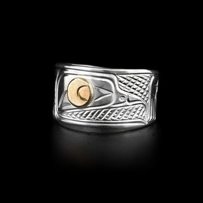 This sterling silver ring has a wide band with carvings on it that depict the Crow. The Crow's eye is made from 14K gold.