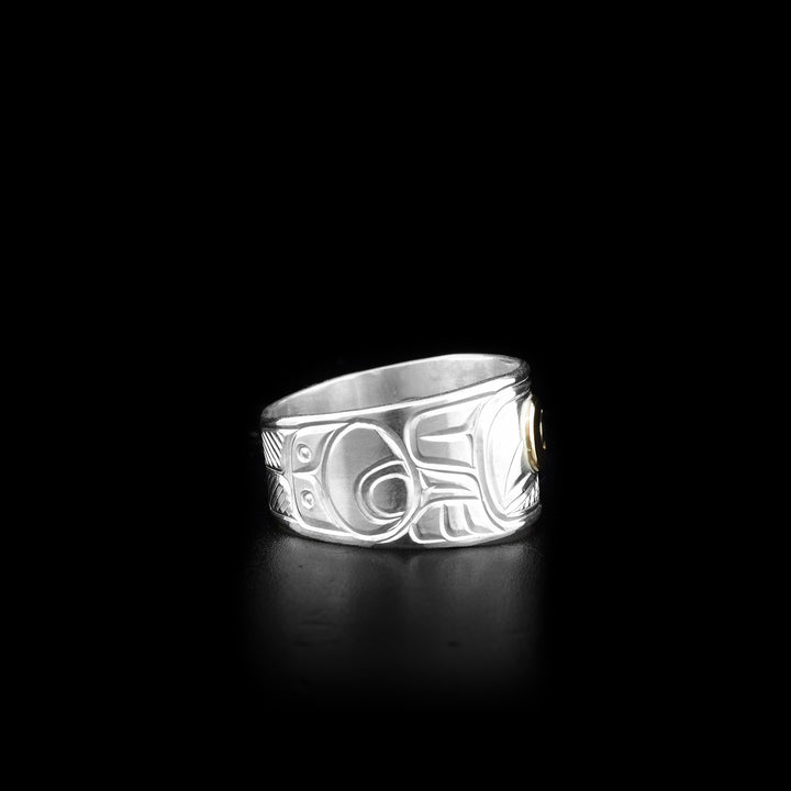 This sterling silver and 14K gold ring has a depiction of the Crow carved into the surface of it. The eye of the Crow is made from 14K gold.