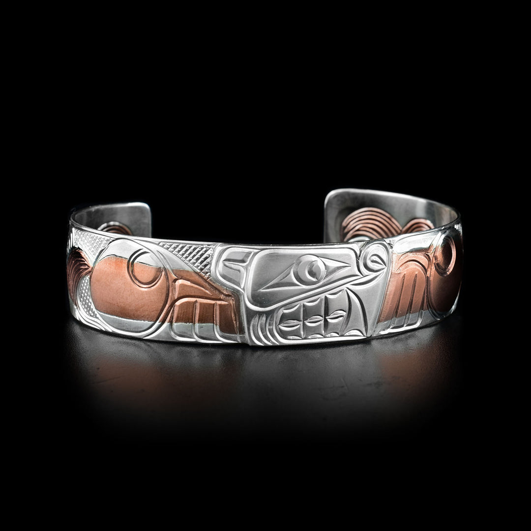 This cuff silver bracelet is made from sterling silver and copper. There are intricate carvings depicting the Bear and many patterns on the band.