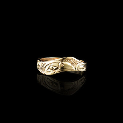 This wavy band ring has a thin, 14K gold band with a wavy appearance. There is a side view of the head of the Raven carved into the surface of the band. around the head, other details of the Raven are carved.