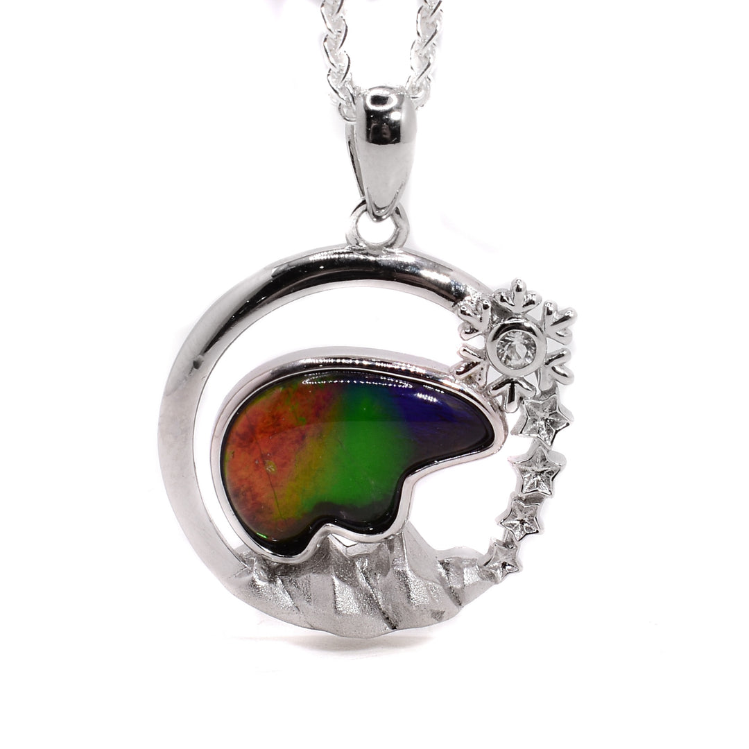 A round sterling silver pendant with an ammolite bear embedded in the middle. There are mountsins under the bear, a snowflake above the bear, and stars under the snowflake. 
