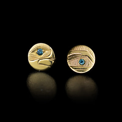 When the earrings are placed next to each other, they create the image of a raven head with a blue diamond in the eye and between the beak. Hand-carved by Haisla artist Hollie Bartlett.