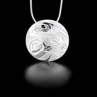 Pendant depicts hummingbirds and flower. Background is cross-hatching. Hidden bail on back. By Haida artist James McGuire.