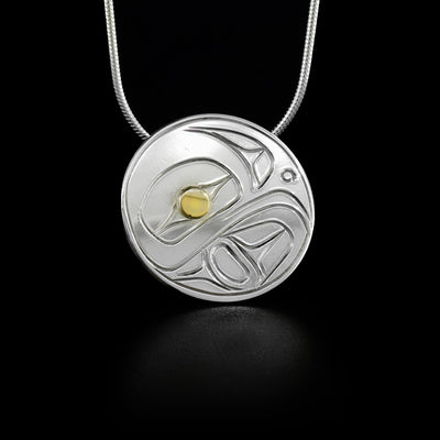 Flat, round sterling silver pendant featuring eagle with 14K yellow gold in eye. Hidden bail on back.