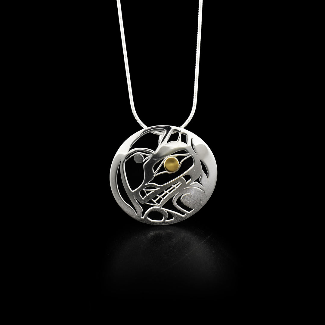 This Wolf and Moon silver gold pendant has 14K gold in the eye of the wolf and features cut out spaces making up design.