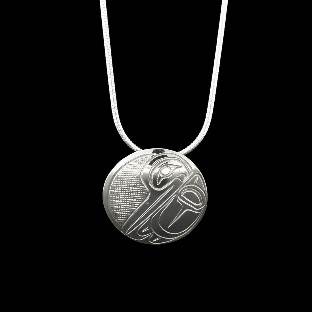 Domed pendant depicts side-view of hummingbird’s head and wing done in ovoids and lines. Background is cross-hatching. Hidden bail on back.