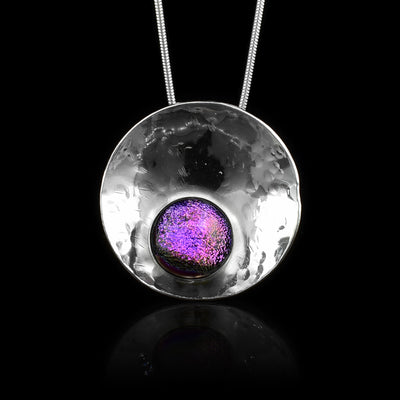 This circle pendant necklace has a circle shaped, sterling silver pendant and is also concaved. There is a purple, fused glass bead that is held in the lower end of the circle pendant.