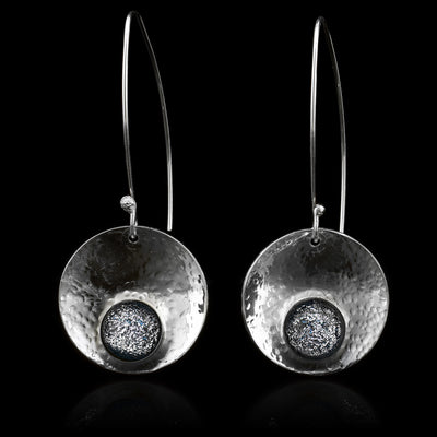 These dangling circle drop earrings have concaved, circle shaped hangs that have been embossed with denim patterned fused glass beads held at the bottom of the hangs. The hangs are held from long wire hooks giving the earrings a long, elegant appearance.