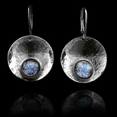 These circle dangle earrings are made using sterling silver and blue and white fused glass beads. The hangs are circle shaped and embossed into a concave shape. The glass beads have interesting patterns in  them and are displayed at the bottom of the hangs.