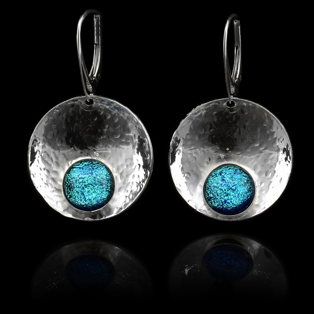 These circle dangle earrings are made using sterling silver and brilliant sky blue fused glass beads. The hangs are circle shaped and embossed into a concave shape. The glass beads have interesting patterns in  them and are displayed at the bottom of the hangs.