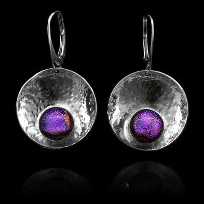 These circle dangle earrings are made using sterling silver and purple fused glass beads. The hangs are circle shaped and embossed into a concave shape. The glass beads have interesting patterns in  them and are displayed at the bottom of the hangs.