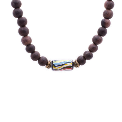 Dark wood beaded necklace. Cylindrical handmade lampworked glass bead, with colourful stripes and black sides, is in the center separated from wood beads by antiqued brass adornments.