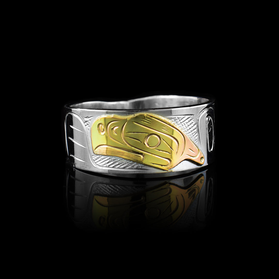 This Graham Henry band made of sterling silver and 10k gold. Featuring a hand-carved Thunderbird legend in gold against a silver band, it showcases premium materials and traditional craftsmanship.