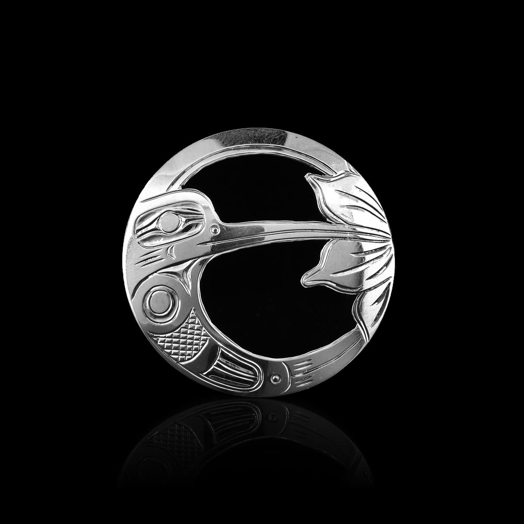 This Hummingbird pin (brooch) is made from sterling silver and has a stainless steel pin in the back. The brooch is circle shaped with carving that depict the Hummingbird and a flower on the surface of it. The pendant is cutout around the design of the Hummingbird and the flower.