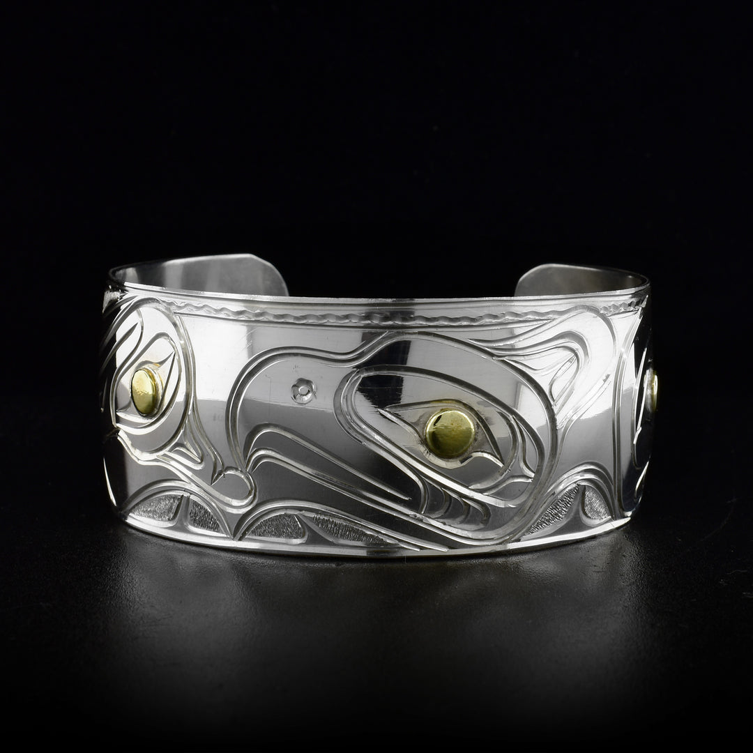 Sterling silver cuff bracelet featuring a thunderbird, raven, hummingbird and an eagle. Brass in eyes. By Kwakwaka’wakw artist Paddy Seaweed.