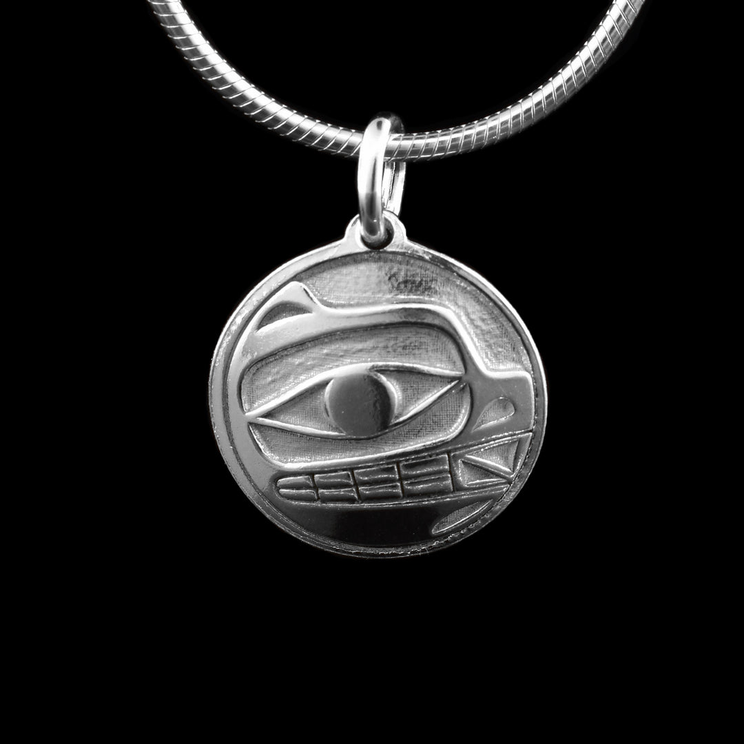 This bear silver pendant has a circle shape made from sterling silver. There is a depiction of the bear cast into the pendant at a side profile. The top half consists of the eye, mouth with teeth showing.
