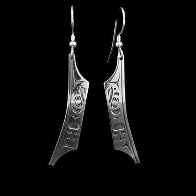 Sterling silver canoe dangle earrings with eagle designs laser-carved into them. By Tahltan artist Grant Pauls.