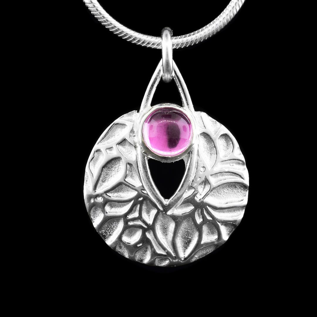 Sterling silver pendant with a beautiful floral patterns, featuring a vibrant pink sapphire top centerpiece