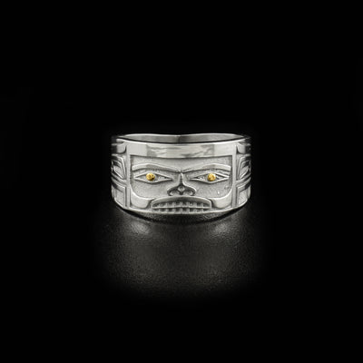 Ring designed to resemble Chilkat bentwood box. Front depicts a face. Pupils are made of 18K gold and rest of ring is sterling silver.