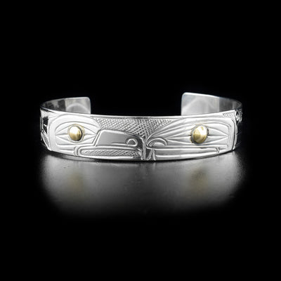 Bracelet features an orca and an eagle facing each other with gold in the eyes. Background is cross-hatching. By Heiltsuk artist Reg Gladstone.