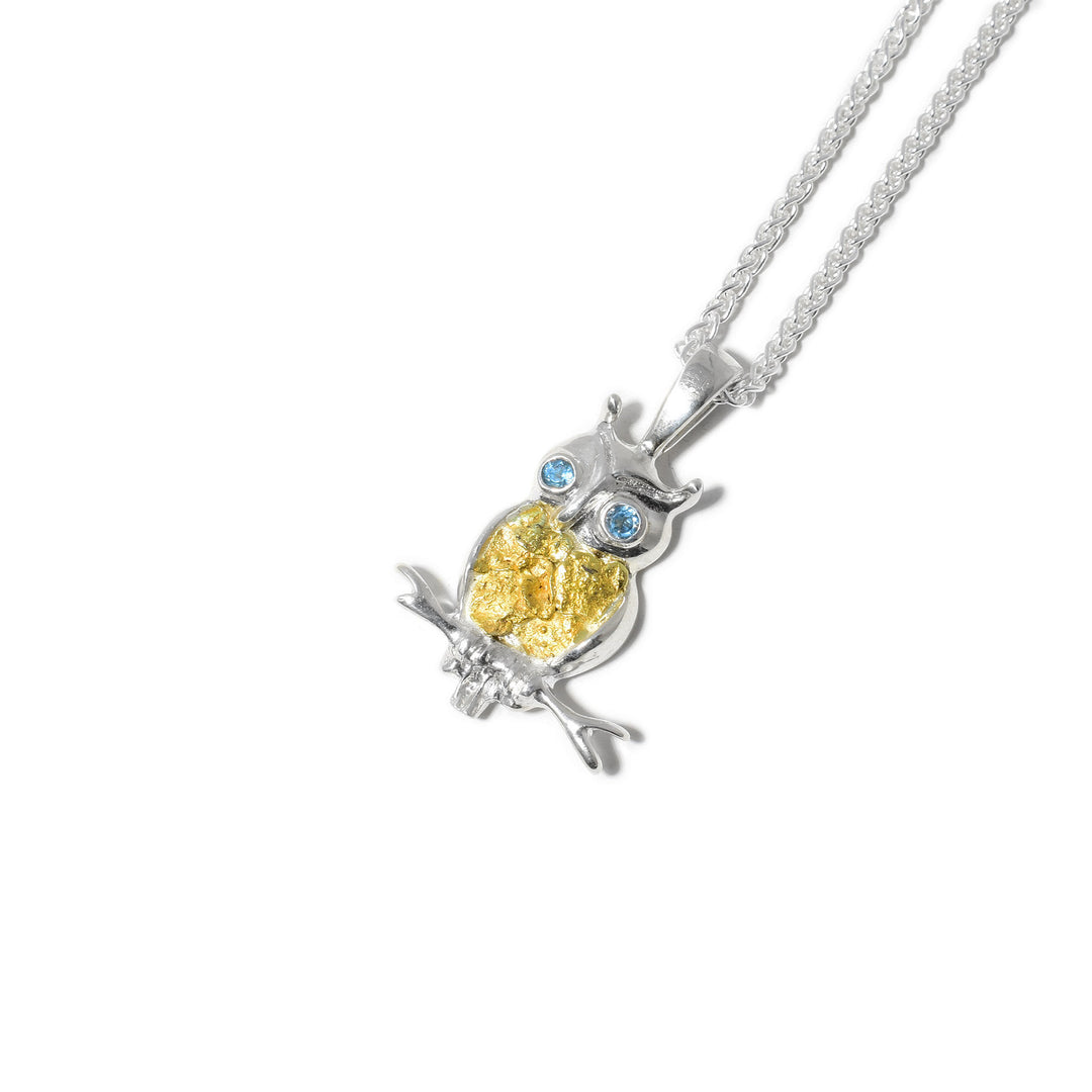 Sterling silver owl pendant with 22K gold nuggets on torso. Eyes are faceted blue topazes. Owl sitting on sterling silver branch.