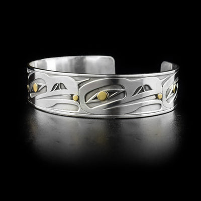 Sterling silver cuff bracelet featuring five raven heads with 14K yellow gold balls in beaks. Eyes also contain 14K yellow gold. Laser-carved design by Tahltan artist Grant Pauls.